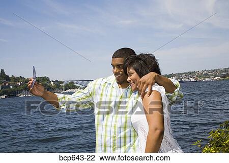Couple taking a picture of themselves by bay View Large Photo Image Stock Image - Couple taking a picture of themselves by bay. Fotosearch