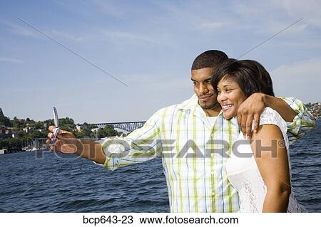 Couple taking a picture of themselves by bay View Large Photo Image Stock Image - Couple taking a picture of themselves by bay. Fotosearch