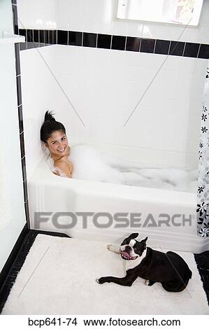 Picture - Dog sitting near woman in bathtub. Fotosearch