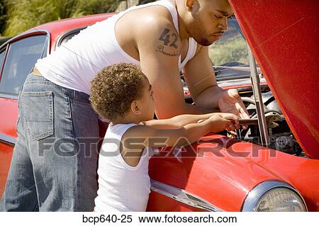 Stock Photography - Father and son checking under car hood. Fotosearch
