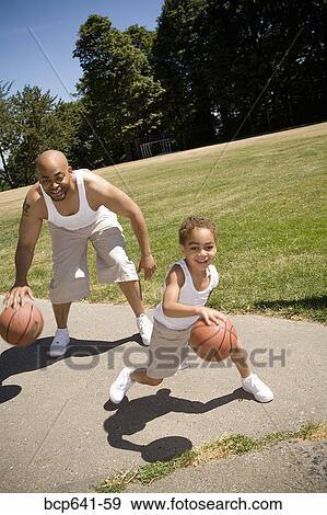 Stock Photo - Father and son dribbling basketballs. Fotosearch