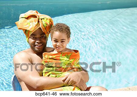 Stock Photograph - Father and son drying off by pool. Fotosearch