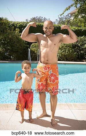 Stock Photo - Father and son flexing muscles by pool. Fotosearch