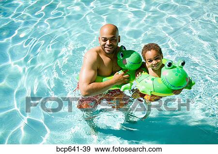 Stock Photo - Father and son playing in pool. Fotosearch