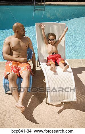 Father and son relaxing by pool View Large Photo Image Picture - Father and son relaxing by pool. Fotosearch