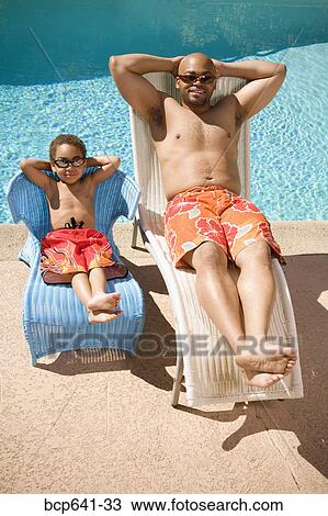 Father and son relaxing by pool View Large Photo Image Stock Image - Father and son relaxing by pool. Fotosearch