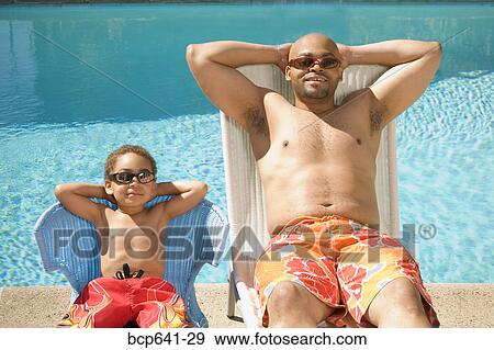 Stock Photo - Father and son relaxing by pool. Fotosearch