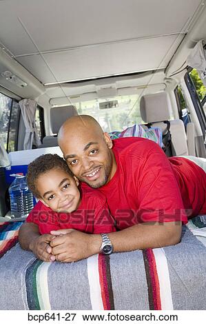 Stock Photo - Father and son sitting in trunk of car with camping gear. Fotosearch