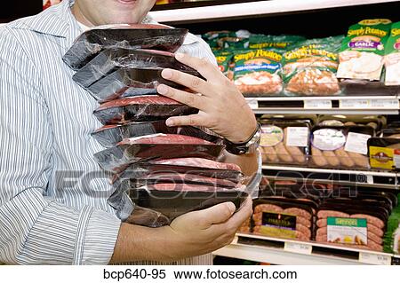 Stock Photography - Man carrying packages of raw meat. Fotosearch