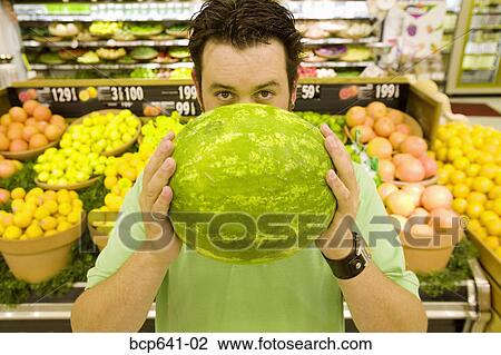 Stock Image - Man holding watermelon in supermarket. Fotosearch