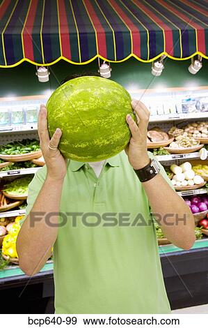 Man holding watermelon in supermarket View Large Photo Image Stock Photo - Man holding watermelon in supermarket. Fotosearch