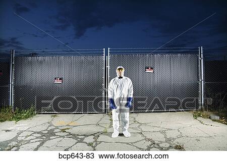 Man in biohazard suit standing outside security gate View Large Photo Image Stock Image - Man in biohazard suit standing outside security gate. Fotosearch