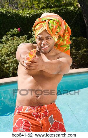 Man in towel turban pointing squirt gun View Large Photo Image Stock Image - Man in towel turban pointing squirt gun. Fotosearch