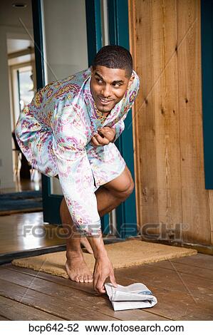 Stock Image - Man picking up newspaper from front porch. Fotosearch