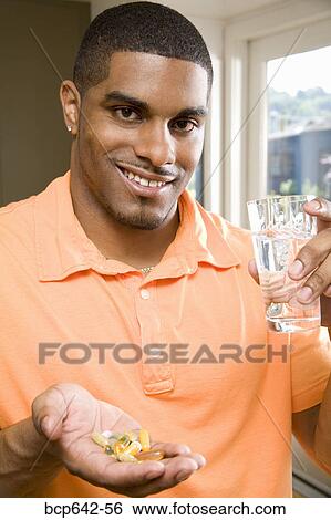 Stock Photograph - Man taking a handful of pills. Fotosearch