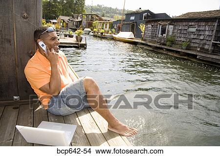 Picture - Man talking on cell phone by canal. Fotosearch