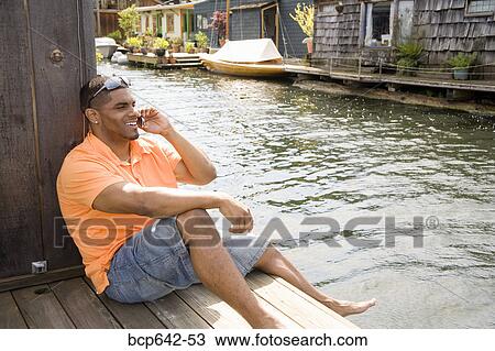 Man talking on cell phone by canal View Large Photo Image Stock Image - Man talking on cell phone by canal. Fotosearch