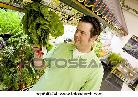 Picture - Man wary of green plant in supermarket. Fotosearch