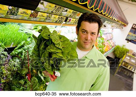 Stock Photography - Man wary of green plant in supermarket. Fotosearch