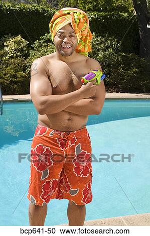 Stock Image - Man wearing towel turban by pool. Fotosearch