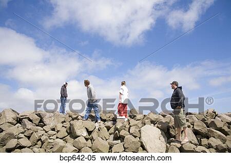 Stock Photography - Men walking over rocky terrain. Fotosearch