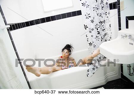 Stock Photo - Pacific Islander, Asian woman blowing bubbles out of bathtub. Fotosearch