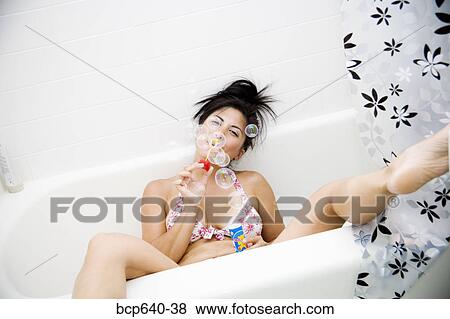 Stock Photo - Pacific Islander, Asian woman blowing bubbles out of bathtub. Fotosearch