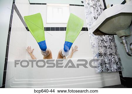 Picture - Pacific Islander, Asian woman wearing flippers in bathtub. Fotosearch