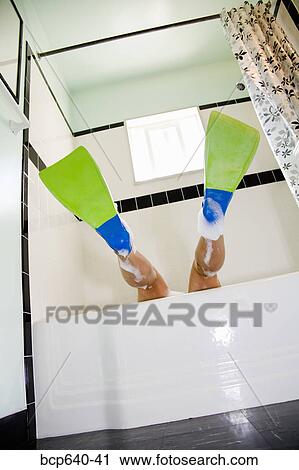 Stock Image - Pacific Islander, Asian woman wearing flippers in bathtub. Fotosearch