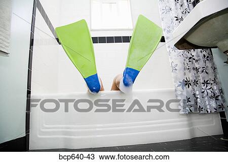 Stock Image - Pacific Islander, Asian woman wearing flippers in bathtub. Fotosearch