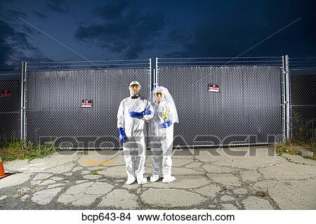 People in biohazard suits standing outside security gate View Large Photo Image Picture - People in biohazard suits standing outside security gate. Fotosearch