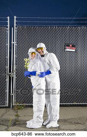 Stock Photograph - People in biohazard suits standing outside security gate. Fotosearch