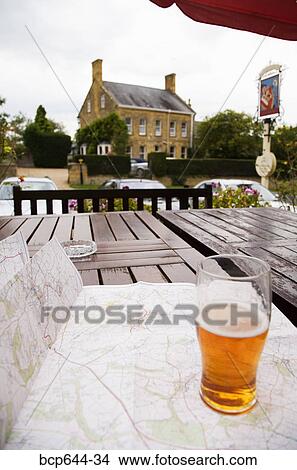 Picture - Pint of beer and map on outdoor table, Gloucestershire, United Kingdom. Fotosearch