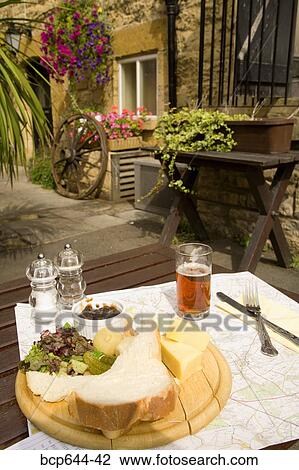Stock Image - Plate of food pinning down map outdoors, Gloucestershire, United Kingdom. Fotosearch