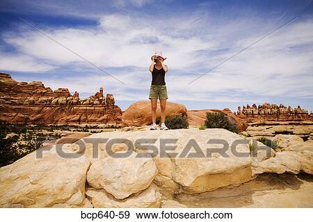 Stock Photo - Tourist looking out over rock formations, Moab, Canyonlands, Utah, United States. Fotosearch