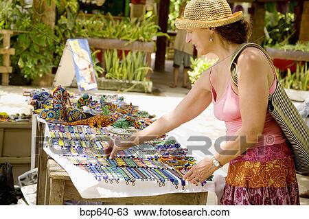 Stock Image - Woman admiring crafts for sale. Fotosearch