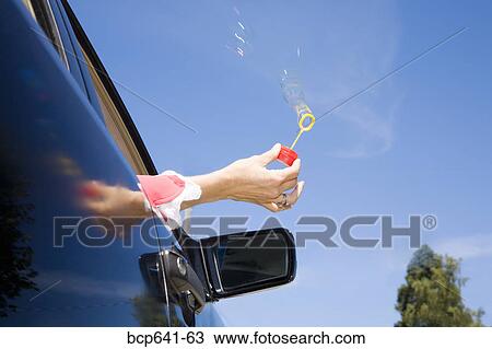 Woman blowing bubbles out car window View Large Photo Image Stock Image - Woman blowing bubbles out car window. Fotosearch