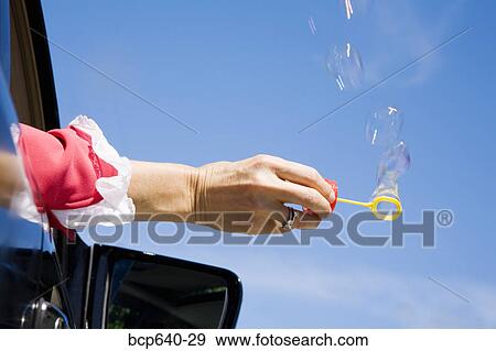 Woman blowing bubbles out car window View Large Photo Image Stock Photo - Woman blowing bubbles out car window. Fotosearch