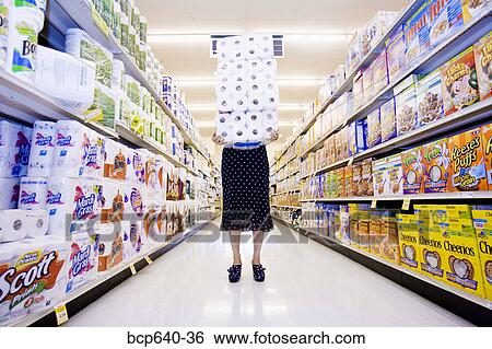 Stock Photograph - Woman carrying stack of toilet paper in supermarket. Fotosearch