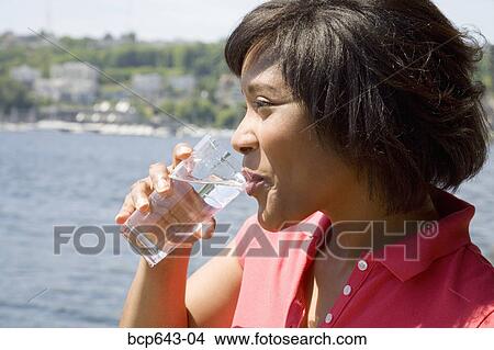 Woman drinking a glass of water View Large Photo Image Picture - Woman drinking a glass of water. Fotosearch