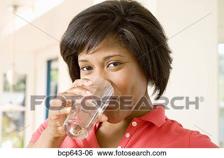 Woman drinking a glass of water View Large Photo Image Stock Photograph - Woman drinking a glass of water. Fotosearch