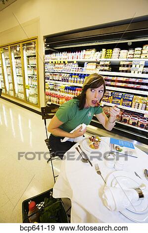 Woman eating dinner in grocery store View Large Photo Image Stock Photo - Woman eating dinner in grocery store. Fotosearch