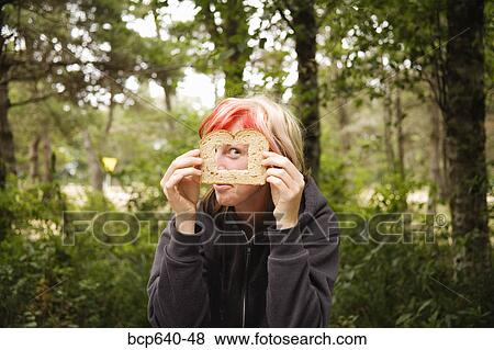 Stock Photo - Woman looking through square in bread outdoors. Fotosearch