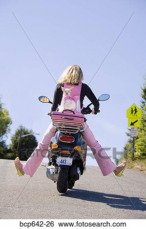 Stock Photograph - Woman riding a scooter with extended legs. Fotosearch
