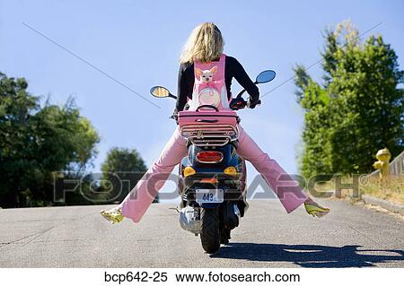 Stock Photography - Woman riding a scooter with extended legs. Fotosearch