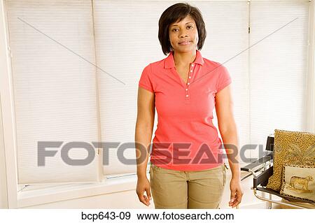 Stock Photo - Woman standing in living room. Fotosearch
