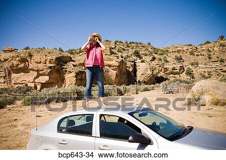 Woman taking picture of desert on top of car View Large Photo Image Picture - Woman taking picture of desert on top of car. Fotosearch