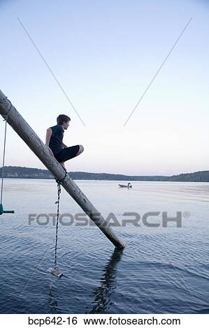 Young boy balancing on pole extending into lake View Large Photo Image Stock Photograph - Young boy balancing on pole extending into lake. Fotosearch