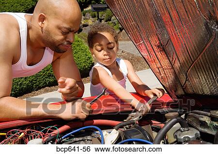 Stock Photograph - Young boy helping his father work on car. Fotosearch