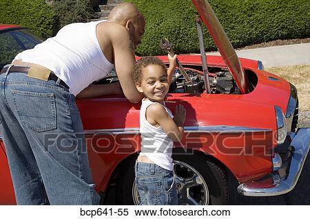 Stock Photography - Young boy helping his father work on car. Fotosearch